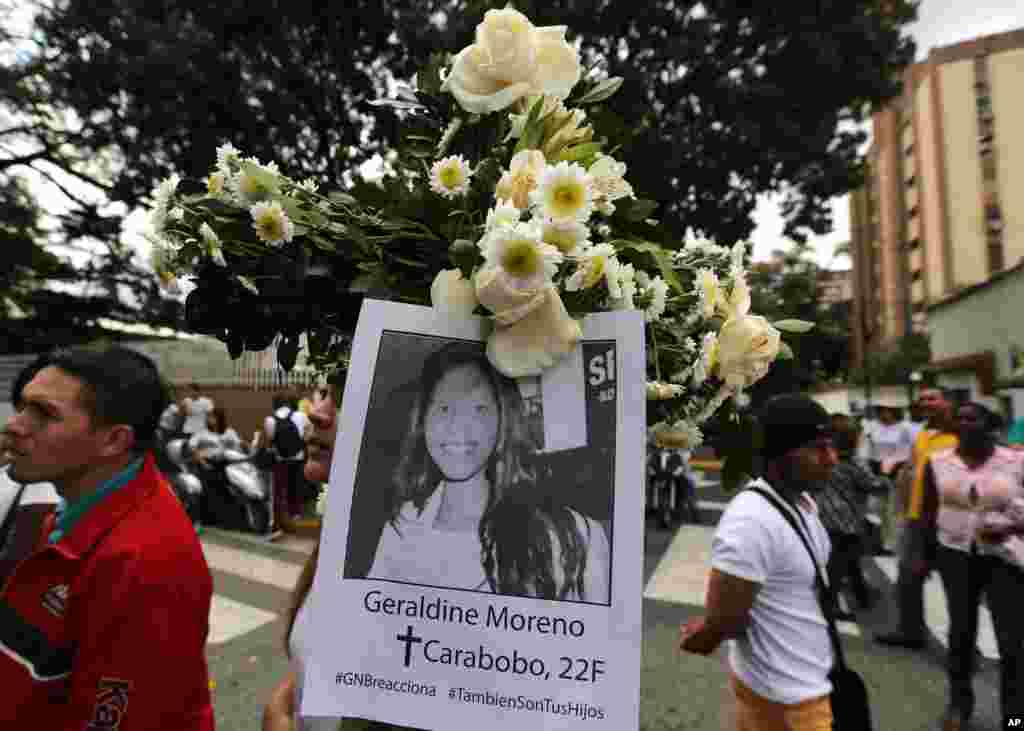 A demonstrator holds a picture of slain student Geraldine Moreno during a women's march to the Bolivarian National Guard headquarters to protest repression against anti-government demonstrators in Caracas, Venezuela, Wednesday, Feb. 26, 2014. Moreno was n