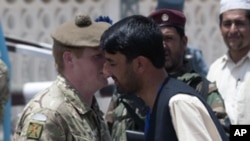 A British army officer (L) receives flowers from an Afghan man during a ceremony to hand over control of security in Lashkar Gah in Helmand province, southern Afghanistan, July 20, 2011.