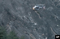 A rescue helicopter flies over debris of the Germanwings passenger jet, scattered on the mountain side, near Seyne les Alpes, French Alps, March 24, 2015.