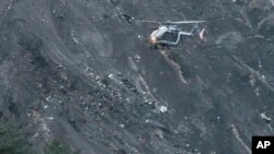 Sebuah helikopter penyelamat terbang di atas puing-puing pesawat Germanwings yang tersebar di Pegunungan Alpen (24/3). (AP/Claude Paris)