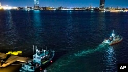 Boyas amarillas que suspenden el helicóptero que se estrelló en el East River flotan junto a un barco de la Policía de Nueva York el domingo, 11 de marzo de 2018.