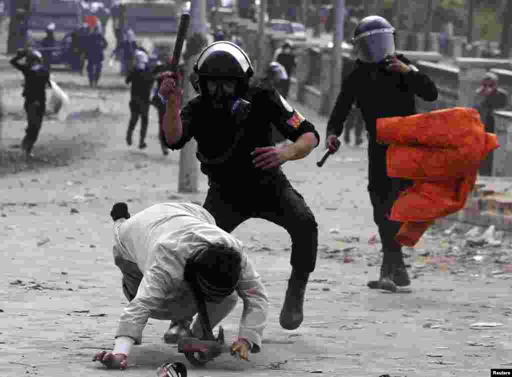 Riot policemen beat a protester opposing Egyptian President Mohamed Morsi, during clashes along Qasr Al Nil bridge, which leads to Tahrir Square in Cairo.