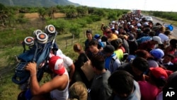 A man holds up a stroller as hundreds of migrants hitching a ride accommodate themselves on the back of truck, between Niltepec and Juchitan, Mexico, Oct. 30, 2018.