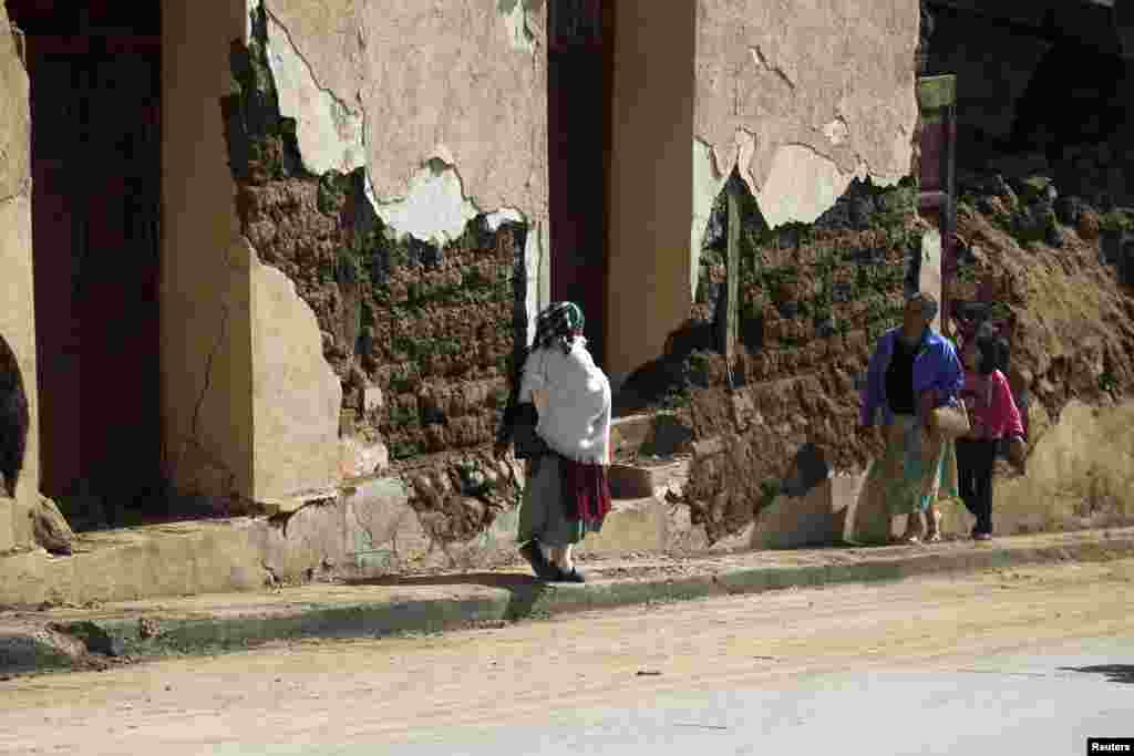 People walk past a damaged house after a 7.4-magnitude earthquake, San Marcos, Guatemala, November 8, 2012.