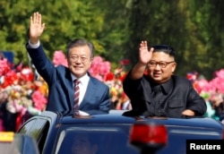 South Korean President Moon Jae-in and North Korean leader Kim Jong Un wave during a car parade in Pyongyang, North Korea, Sept. 18, 2018.