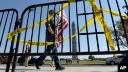 FILE - Pedestrians walk past a barricade preventing them from entering the World War II Memorial in Washington, Oct. 2, 2013, during a government shutdown. Another government shutdown looms if Congress does not agree on funding continued operations by Dec. 8.