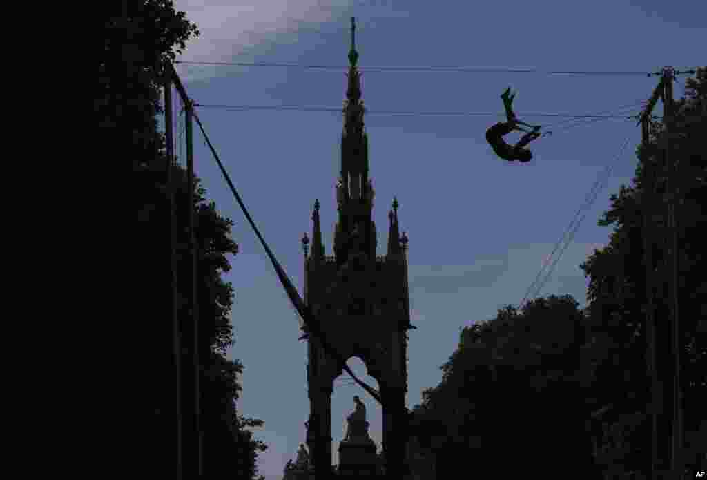 A man is silhouetted as he takes part in a Trapeze School near the Albert Memorial Statue in Kensington Gardens in London.