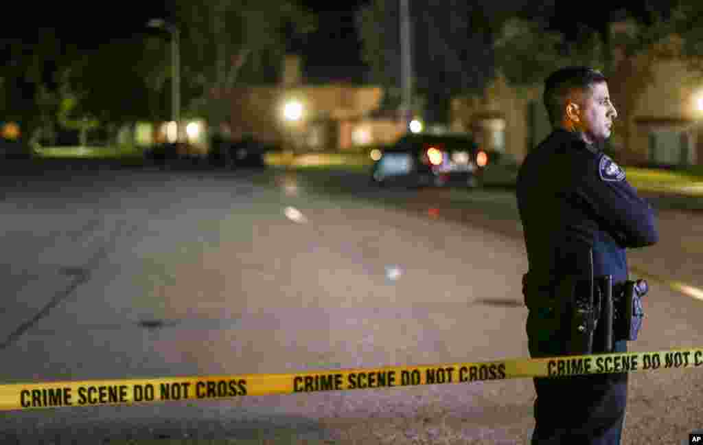 A police officer stands guard inside an area roped off with crime scene tape near a home being investigated by police on Dec. 3, 2015, in Redlands, Calif. 