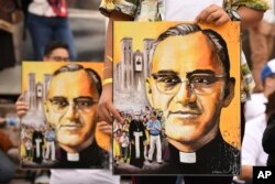 Salvadoreños en procesión sostienen afiches del arzobispo Óscar Arnulfo Romero en San Salvador, el sábado 13 de octubre de 2018. Romero fue elevado a la santidad por el papa Francisco el domingo 14 de octubre de 2018, junto con el papa Paulo VI y otros cinco beatos.