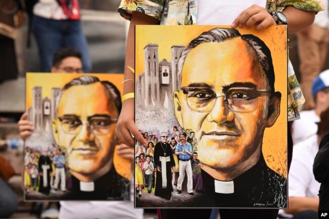 Salvadoreños en procesión sostienen afiches del arzobispo Óscar Arnulfo Romero en San Salvador, el sábado 13 de octubre de 2018. Romero fue elevado a la santidad por el papa Francisco el domingo 14 de octubre de 2018, junto con el papa Paulo VI y otros cinco beatos.