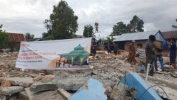 Sekelompok warga berdiri diatas puing-puing bangunan masjid yang roboh akibat gempa di dusun Petakeang, Kecamatan Tapalang, Sulawesi Barat. Jumat (5/1/2021). (Foto: VOA/Yoanes Litha)