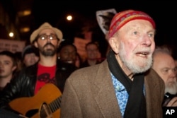 FILE - Activist musician Pete Seeger, 92, left, marches with nearly a thousand demonstrators sympathetic to the Occupy Wall Street protests for a brief acoustic concert in Columbus Circle in New York, Oct. 21, 2011.