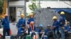 FILE - Cambodian migrant construction workers wait for their transport home outside a building site in downtown Bangkok, Thailand.