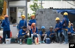 FILE - Cambodian migrant construction workers wait for their transport home outside a building site in downtown Bangkok, Thailand, Dec. 12, 2016.