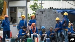 FILE - Cambodian migrant construction workers wait for their transport home outside a building site in downtown Bangkok, Thailand.