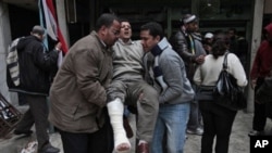 Anti-government demonstrators carry a man wounded during clashes with pro-government protesters, at a makeshift medical triage station, near Tahrir square, the center of anti-government demonstrations, in Cairo, Egypt, Wednesday, Feb. 2, 2011. Thousands o