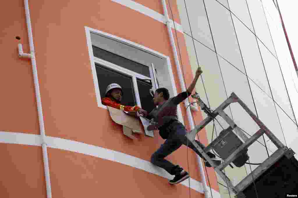 A firefighter pulls a worker after he was trapped on a hanging platform in Liu&#39;An, Anhui province, China, Sept. 9, 2013. The platform was hanging from the building at a height of 18 meters outside a building when it accidentally went out of control, according to local media. 
