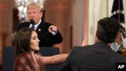 Presiden Donald Trump menunjuk ke wartawan CNN, Jim Acosta, sedangkan seorang staf Gedung Putih mengambil mikrofon dari tangan 