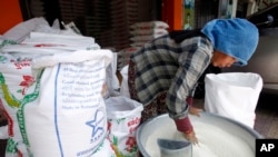 FILE: A Cambodian vendor cleans her rice as she prepares it to sell at a rice store in Phnom Penh, Cambodia, Saturday, April 27, 2019. Cambodia's close friend China agreed to buy 400,000 tons of rice from Cambodia for this year and next year. (AP Photo/Heng Sinith)