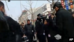 美国之音记者何宗安高举双手抗议被警察推挤的镜头(照片中右侧带眼镜的女记者)