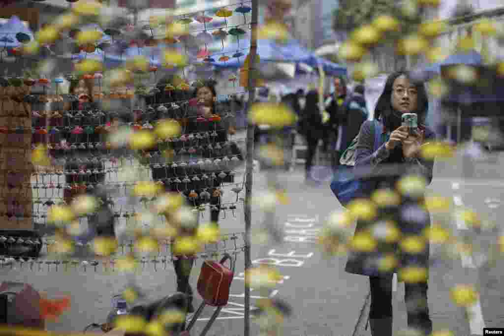 People take pictures of miniature paper umbrellas, symbols of the pro-democracy movement, in the area occupied by protesters at Causeway Bay shopping district, in Hong Kong. Police arrested nearly 250 activists on Thursday and cleared most of the main protest site near the Central business district, marking an end to more than two months of street demonstrations. 