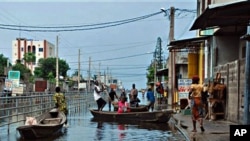 Residents board canoes in a city street flooded by an overflowing drainage canal, in the Saint Martin neighborhood of Cotonou, Benin, 09 Oct. 2010