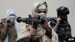 FILE - Former Afghan Taliban fighters carry their weapons before handing them over as part of a government peace and reconciliation process at a ceremony in Jalalabad, Jan. 12, 2016. 