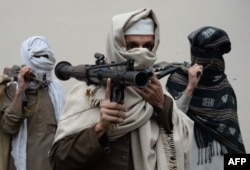 Former Afghan Taliban fighters carry their weapons before handing them over as part of a government peace and reconciliation process at a ceremony in Jalalabad, Jan. 12, 2016.