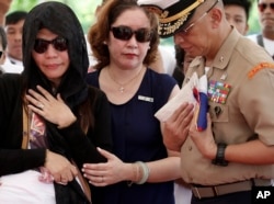 Philippine Marine Brig.Gen. Alvin Parreno (right) prepares to hand the folded national flag to Leslie Abad (left) the widow of First LT. Raymond Abad of the Philippine marines, June 20, 2017, at the Heroes Cemetery in Taguig city, east of Manila, Philippines. Abad was one of the 13 marines killed June 9 in fighting between government forces and Muslim militants in Marawi city.