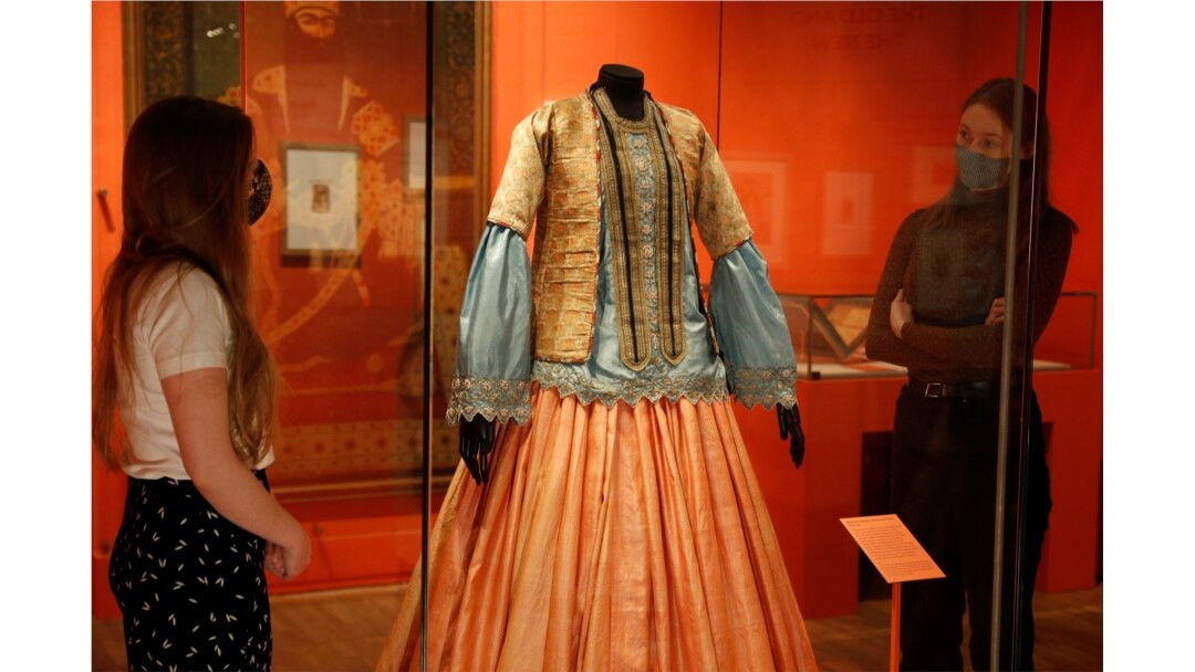 Karyawan museum V&A memperhatikan busana perempuan dari 1840-50 yang dipamerkan di pameran Epic Iran di London, 25 Mei 2021. (Foto: Peter Nicholls/Reuters)