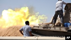 A tank belonging to the Western Shield, a branch of the Libya Shield forces, fires during a clash with rival militias around the former Libyan army camp, Camp 27, west of Tripoli, Aug. 22, 2014. 