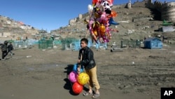 A young boy sells balloons in Kabul, March 23, 2017. An aid group said Thursday that nearly a third of all children in war-torn Afghanistan are unable to attend school, leaving them at increased risk of child labor, recruitment by armed groups, early marriage and other forms of exploitation. 