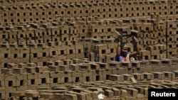 FILE - A laborer carries bricks at a kiln in Karjat, India, March 10, 2016. 