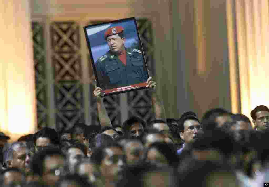 一个人2013年3月5日在尼加拉瓜马拉瓜举行的一次示威期间，手持委内瑞拉总统查韦斯遗像。