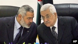 Palestinian Authority President Mahmoud Abbas, right, and Palestinian Prime Minister Ismail Haniyeh of Hamas, left, speak as they head the first cabinet meeting of the new coalition government at Abbas' office, in Gaza City, March 2007 (file photo)