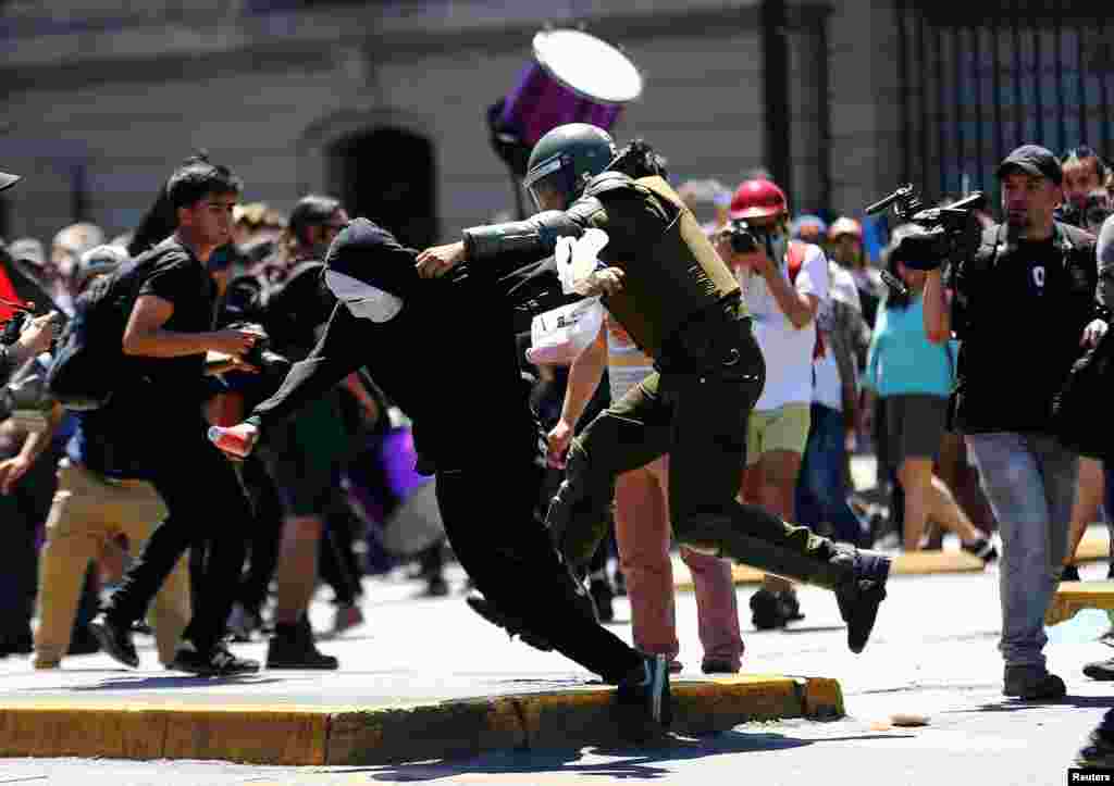 A demonstrator is detained by a riot policeman during a protest march by Mapuche Indian activists against Columbus Day in downtown Santiago, Chile.