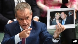 2017年6月14日在一次议会听证会上，澳大利亚反对党领袖硕顿展示黄向墨和时任外长毕晓普的合影（美联社）