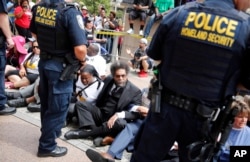 Cornel West, center, joins other protesters sitting on the steps of the Thomas F. Eagleton Federal Courthouse as members of the Federal Protective Service stand watch, Aug. 10, 2015, in St. Louis.