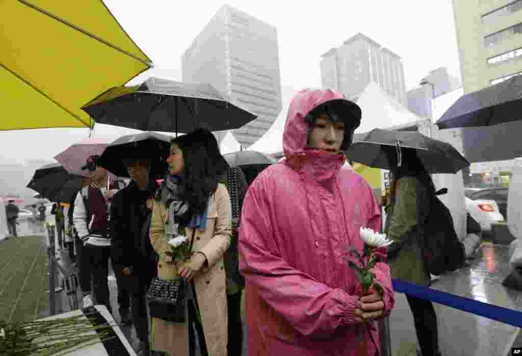 People pay tribute to victims of the sunken ferry Sewol outside a temporary memorial in Seoul, April 16, 2015.
