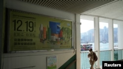 资料照片：一名行人走过香港立法会选举的广告（2021年12月1日）