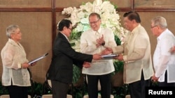 FILE - Philippine President Benigno Aquino, center, applauds as Moro Islamic Liberation Front chief negotiator Mohagher Iqbal, second from left, shakes hands with Senate President Franklin Drilon, second from right, at the presidential palace in Manila, September 10, 2014.