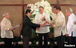 FILE - Philippine President Benigno Aquino (C) applauds as Moro Islamic Liberation Front (MILF) chief negotiator Mohagher Iqbal (2nd L) shakes hands with Senate President Franklin Drilon (2nd R) during the turnover ceremony of the draft Bangsamoro Basic Law (BBL) at the presidential palace in Manila, September 10, 2014.