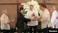 Philippine President Benigno Aquino (C) applauds as Moro Islamic Liberation Front (MILF) chief negotiator Mohagher Iqbal (2nd L) shakes hands with Senate President Franklin Drilon (2nd R) during the turnover ceremony of the draft Bangsamoro Basic Law (BBL