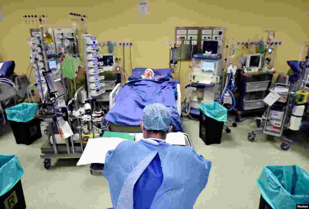 A member of the medical staff in a protective suit is seen in front of a patient diagnosed with coronavirus disease in an intensive care unit at the San Raffaele hospital in Milan, Italy.