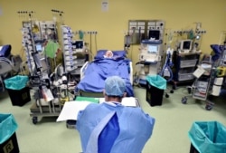 A member of the medical staff in a protective suit is seen in front of a patient diagnosed with coronavirus disease in an intensive care unit at the San Raffaele hospital in Milan, Italy.