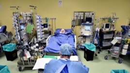 A member of the medical staff in a protective suit is seen in front of a patient diagnosed with coronavirus disease in an intensive care unit at the San Raffaele hospital in Milan, Italy.