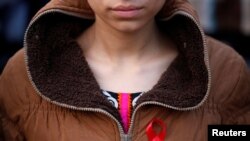 FILE - A woman with a red ribbon pin takes part in a HIV/AIDS awareness campaign ahead of World AIDS Day, in Kathmandu, Nepal, Nov. 30, 2016.