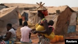 FILE - A woman carries her child in a camp sheltering internally displaced people next to the M'Poko international airport, February 13, 2016.