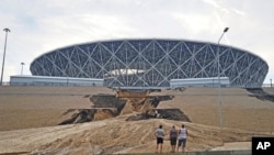 Trois hommes regardent un glissement de terrain important sur une digue après une lourde pluie à côté de la Volgograd Arena,, Russie, 15 juillet 2018. 