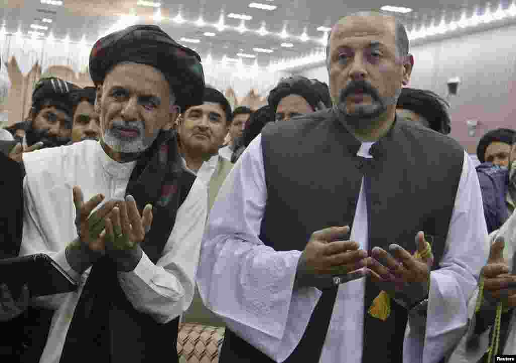 Hashmat Karzai (right), cousin of Afghan President Hamid Karzai, and Afghan presidential candidate Ashraf Ghani pray during a presidential campaign in Kandahar, June 6, 2014.